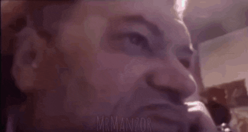 a close up of a man 's face with a purple background and the words `` mr manzor '' written on it .