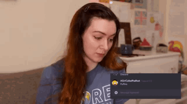 a woman wearing a blue shirt with the word re on it is sitting on a couch