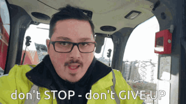 a man wearing glasses and a yellow jacket says " do n't stop don 't give up "