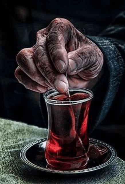 a close up of a person 's hand pouring tea into a glass .