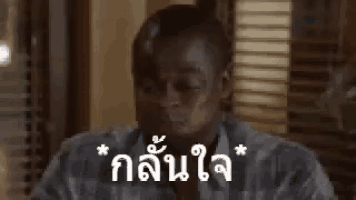 a man in a blue shirt is sitting in front of a window with a foreign language written on it .