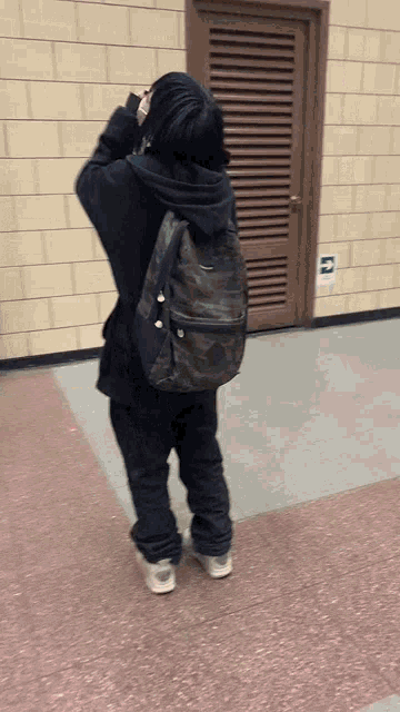 a person standing in front of a door with a green exit sign