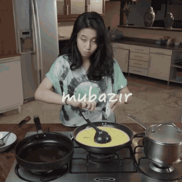 a woman in a green shirt is cooking on a stove and the word mubariz is visible