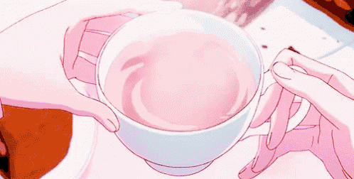 a person is holding a cup of pink liquid in their hand .