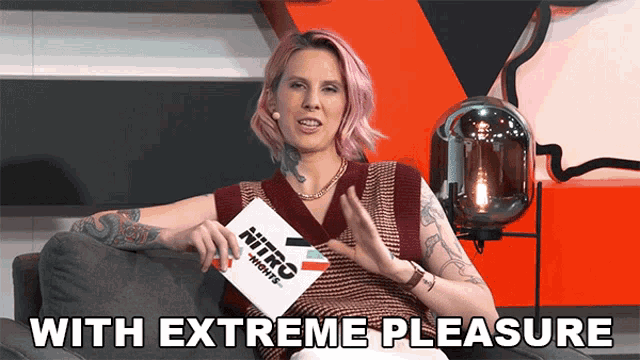 a woman with pink hair is sitting on a couch holding a nitro nights sign