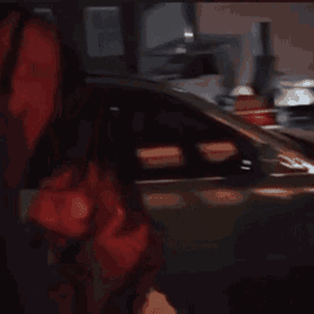 a blurry picture of a man standing next to a car .
