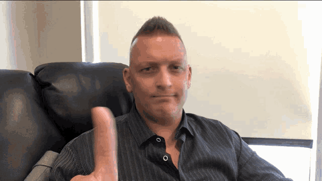 a man sitting in a chair with his thumb up