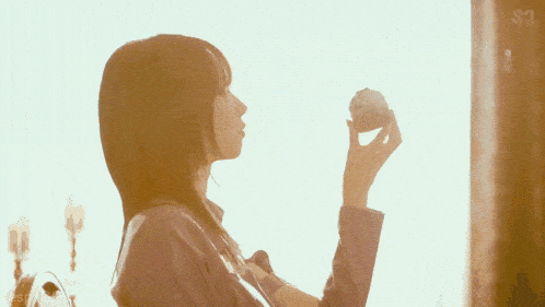 a woman is holding a cupcake in front of a window with the letters s on it