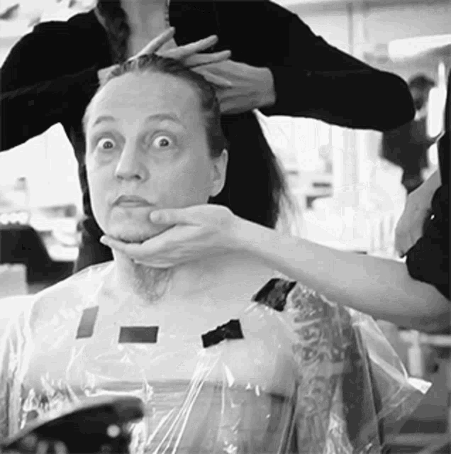 a man with a beard is getting his hair cut
