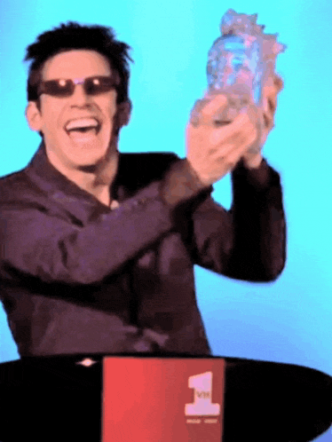 a man wearing sunglasses holds up a trophy in front of a sign that says vh1