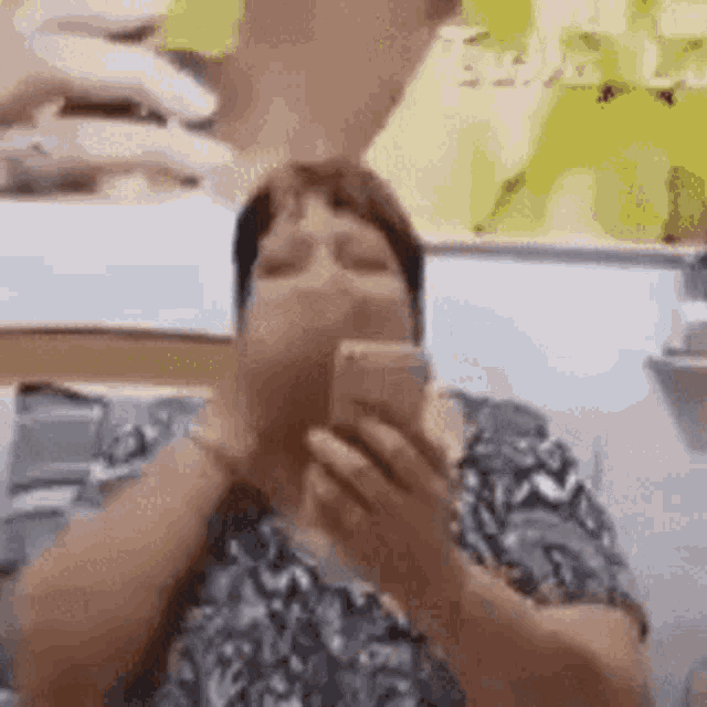 a woman is holding a cell phone in her hand and covering her mouth with her hand .