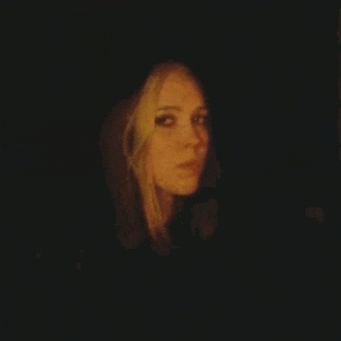 a woman is looking at the camera in the dark .