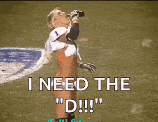a woman in a football uniform is drinking from a bottle on a football field .