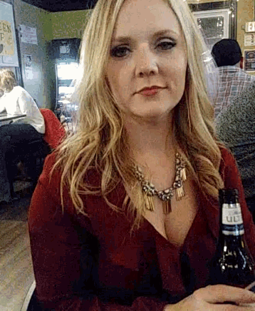 a woman in a red top is holding a beer bottle
