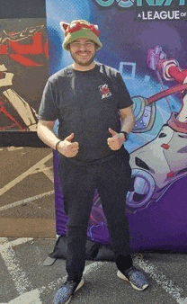 a man wearing a cat hat is giving a thumbs up in front of a league of legends sign .
