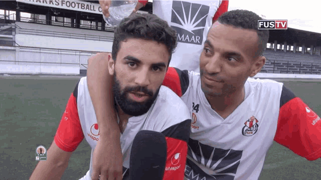 two soccer players are posing for a photo and one has the number 14 on his shirt