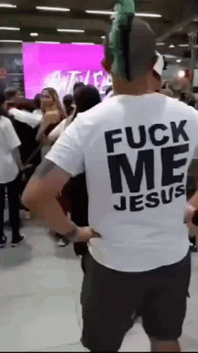 a man with a green mohawk is wearing a white shirt that says fuck me jesus