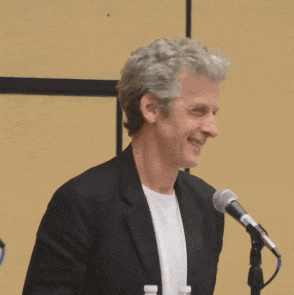 a man in a suit is smiling in front of a microphone .