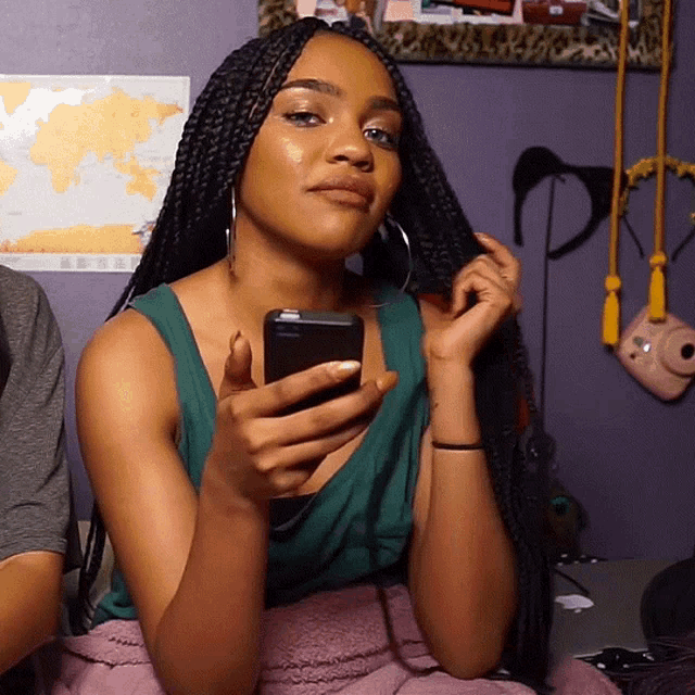 a woman with braids is holding a cell phone