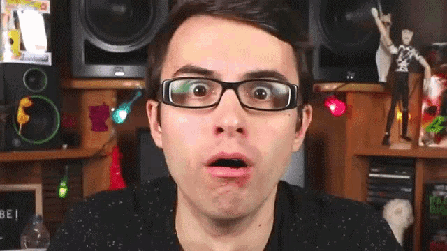 a man wearing glasses makes a funny face in front of a sign that says be