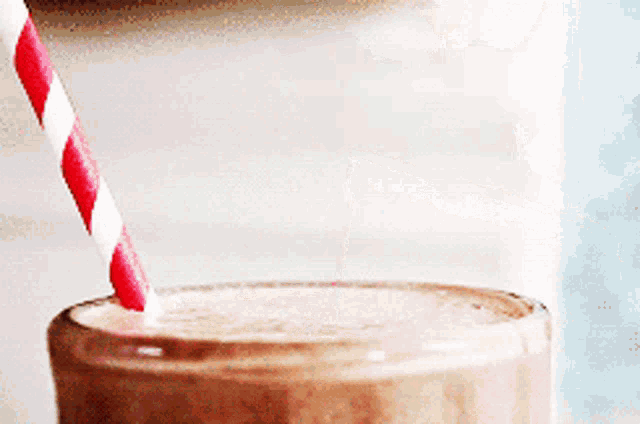 a close up of a milkshake with a red and white straw