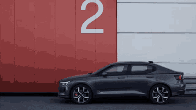 a car is parked in front of a red wall with the number 2 painted on it