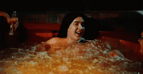 a man and a woman are laying in a hot tub at night .