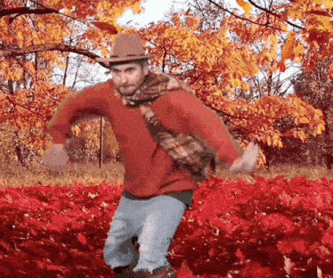 Silly GIF of a man with a scarf dancing overenthusiastically in falling leaves