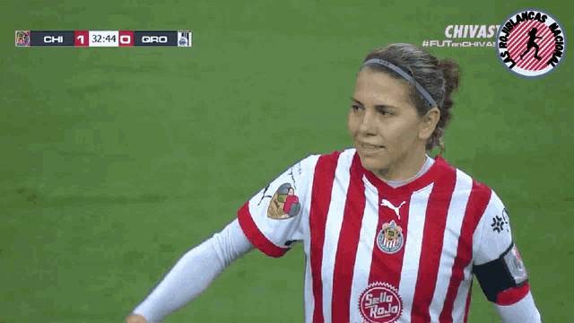 a female soccer player wearing a red and white striped shirt with chivas on the front