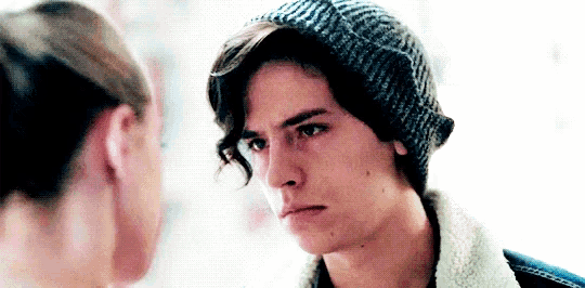 a man in a beanie is looking at a woman in a sweater .