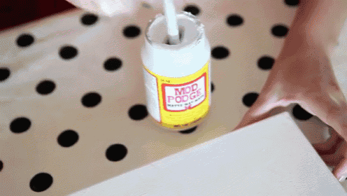 a bottle of mod podge with a brush on top of it