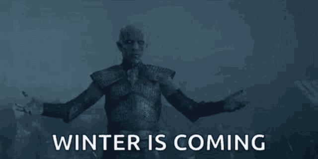 a man in armor is standing in front of a crowd with the words `` winter is coming '' behind him .