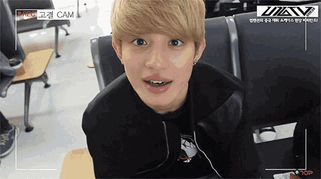 a young man sitting in a waiting room with a camera recording him and the words cam on the bottom
