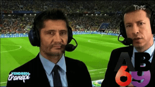 two men wearing headphones are talking in front of a soccer field that says vendredi transpix