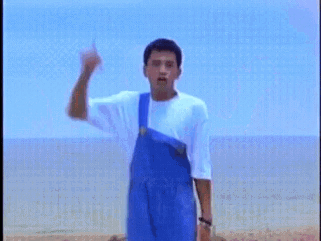 a man in a white shirt is dancing on a beach with chinese writing on the screen .