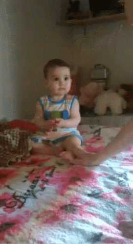 a baby is sitting on a bed with a blanket that says disney