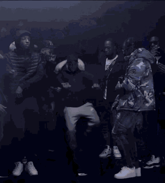 a man wearing nike sweatpants is kneeling down in front of a crowd