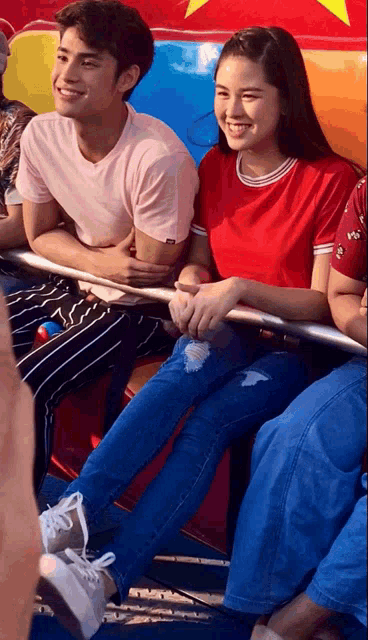 a girl in a red shirt sits next to a man in a pink shirt