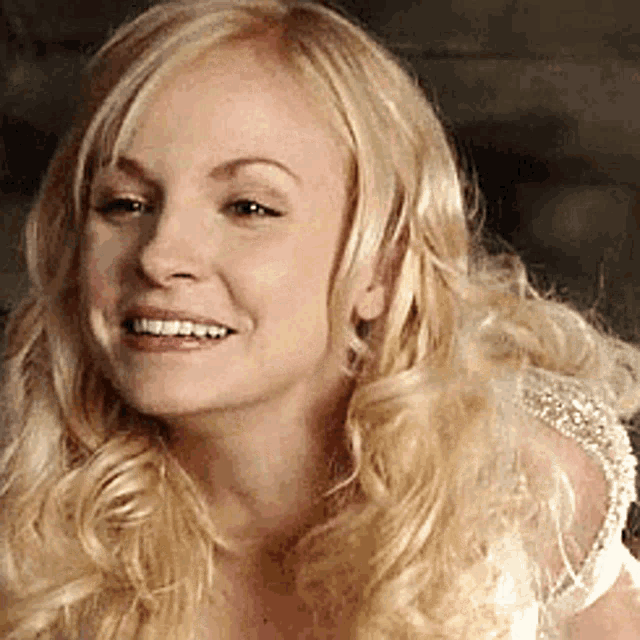 a woman with blonde hair is smiling for the camera .