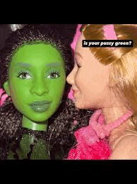 two barbie dolls are kissing each other and one of them is green .