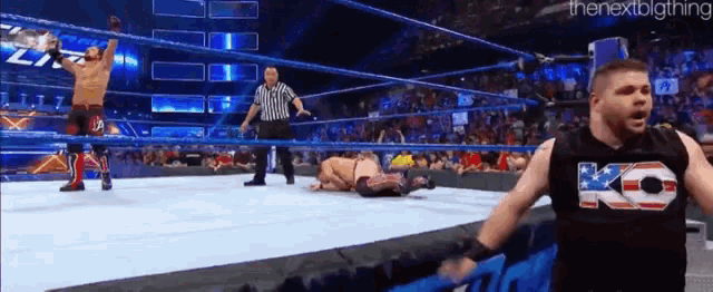 a wrestler wearing a ko shirt is standing in a wrestling ring