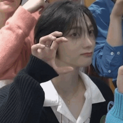 a woman with short hair is sitting in a crowd of people and making a funny face .