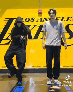 two men are dancing in front of a los angeles lakers poster