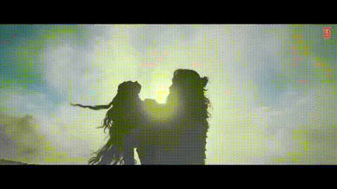 a man and a woman are standing next to each other in front of a waterfall .