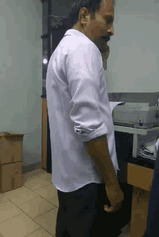 a man in a white shirt is talking on a cell phone