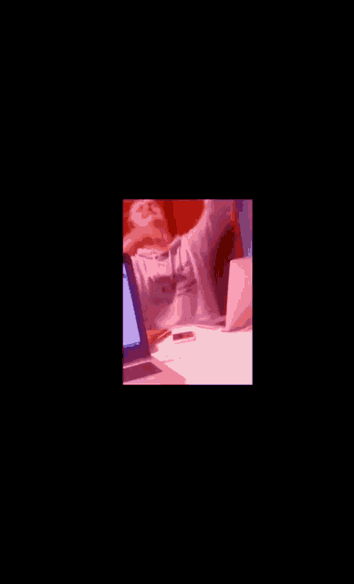 a man sitting at a desk with a laptop and a sweatshirt that says ' a ' on it