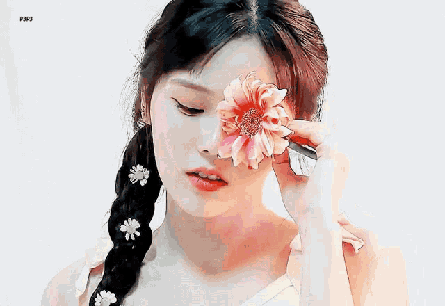 a girl with a braid is holding a flower in front of her eye .