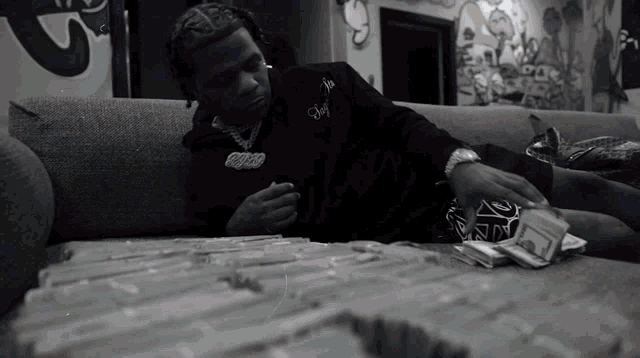 a black and white photo of a man laying on a couch surrounded by money