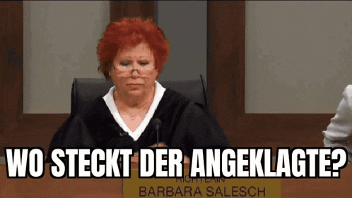 a woman with red hair is sitting in a courtroom with a microphone .