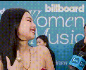 a woman talking into a microphone in front of a billboard that says women music